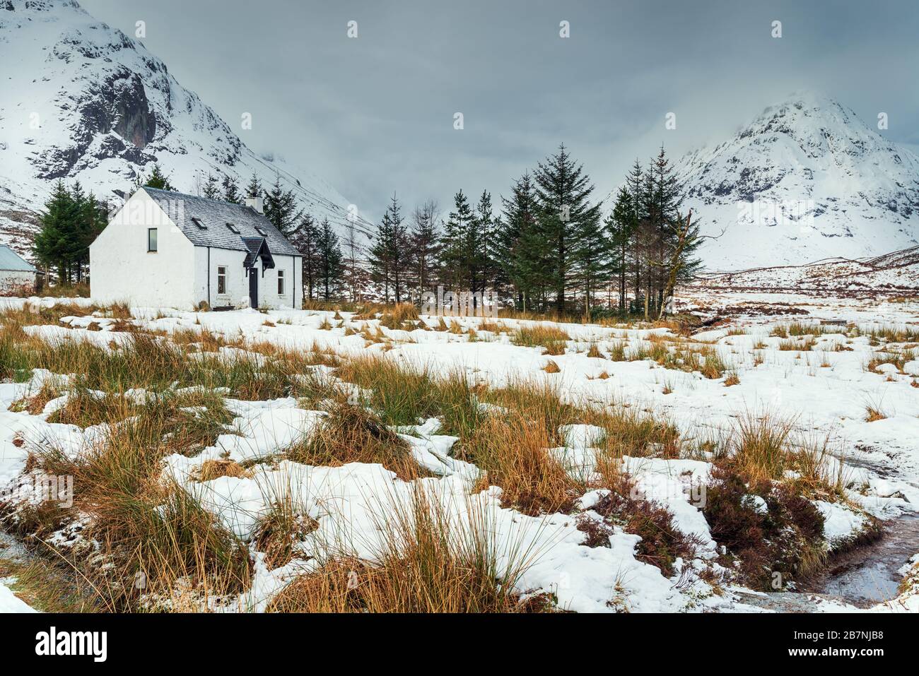 Un remoto cottage di montagna nella neve a Glencoe nelle Highlands della Scozia Foto Stock