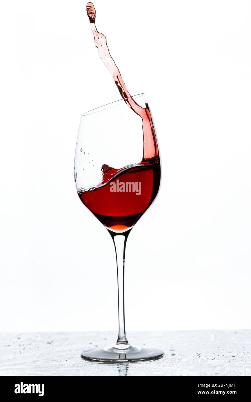 Vista ravvicinata di schizzi di vino rosso in vetro isolato su sfondo bianco. Foto Stock