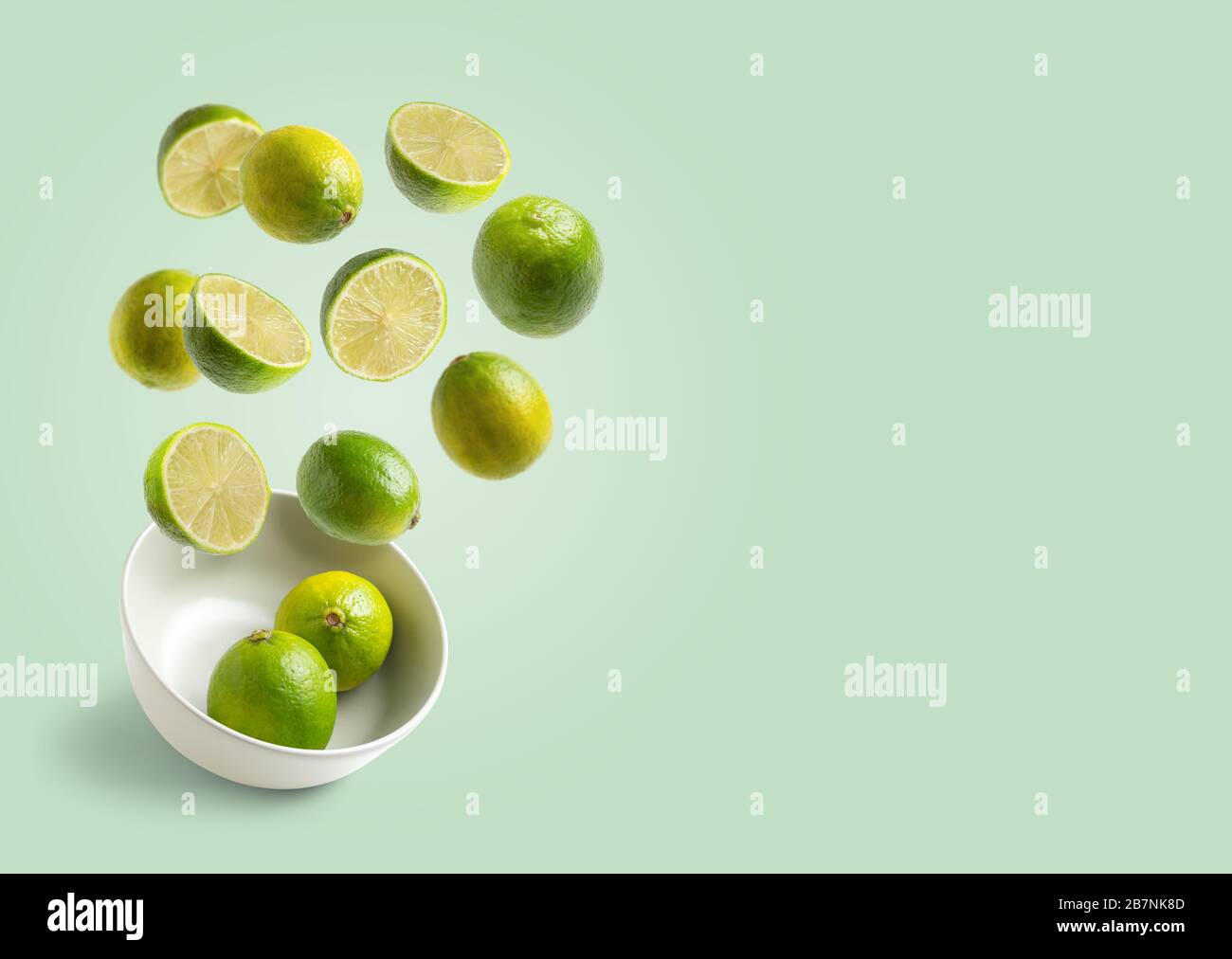 limes volare in ciotola bianca su sfondo verde con spazio per la copia Foto Stock