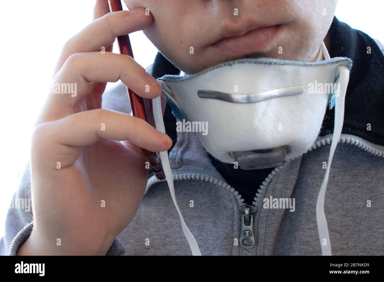 Un uomo in una maschera respiratoria facciale effettua una chiamata telefonica. Respiratore sul collo. Uomo faccia da vicino. Concetto di allarme per virus o malattie Foto Stock