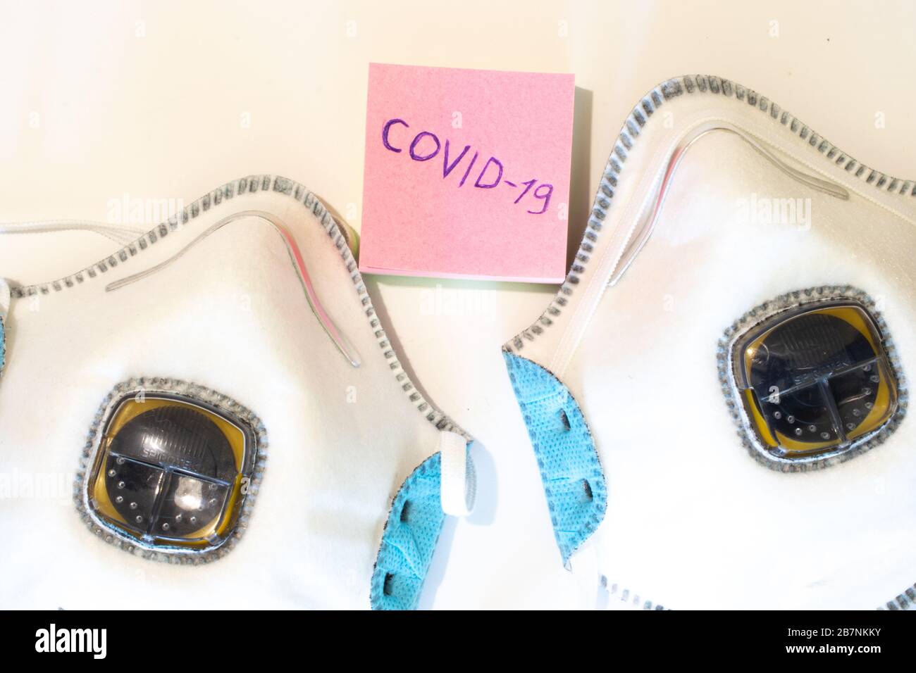 Maschera vista superiore e parola Covid-19 su carta primo piano. Respiratore medico. Concetto di assistenza sanitaria. Il coronavirus è un virus pandemico originario della Cina Foto Stock