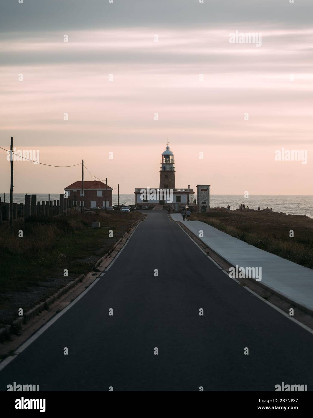 Bellissimo faro alla fine della lunga strada al tramonto in Galizia, Spagna Foto Stock