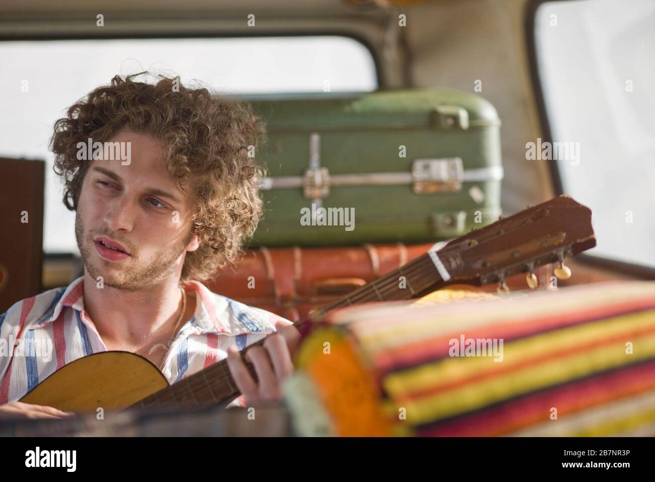 Giovane uomo di suonare una chitarra all'interno di un furgone. Foto Stock