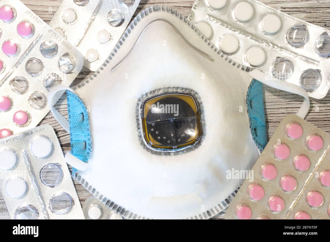 Maschera respiratore vista dall'alto da vicino con pillole e compresse. Flat Lay concetto di salute e protezione personale contro le malattie. Infezioni e. Foto Stock