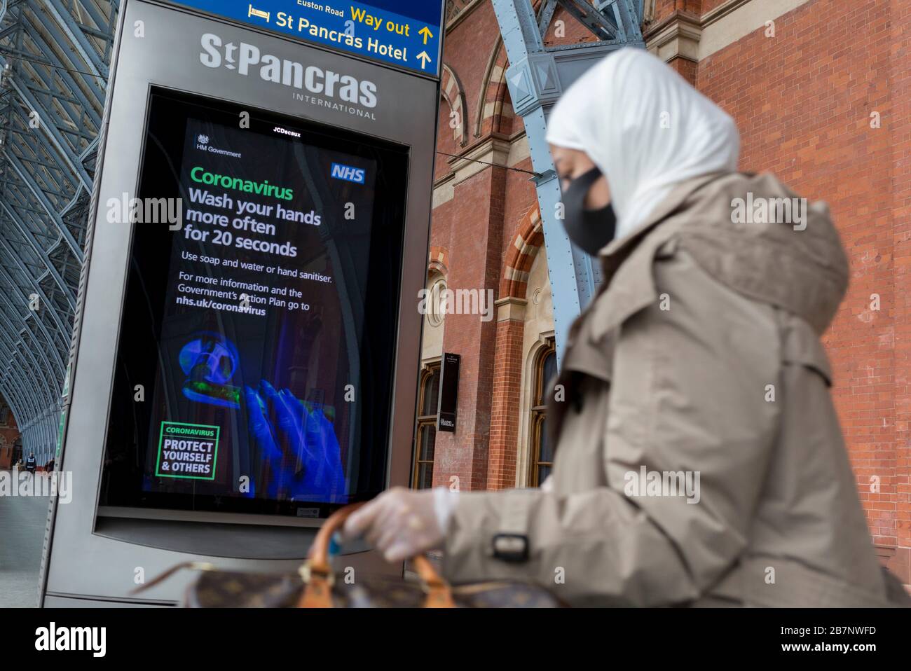 Come il governo britannico ha esortato tutti i britannici a evitare viaggi non essenziali all'estero per combattere la pandemia di Coronavirus in Gran Bretagna, i passeggeri delle ferrovie passano attraverso un annuncio digitale di informazione pubblica da parte del governo e il NHS (National Health Service) dice al pubblico di lavarsi le mani in modo approfondito, In un atrio insolitamente tranquillo nella stazione ferroviaria di St. Pancras, il 17 marzo 2020, a Londra, Inghilterra, il capolinea londinese dei servizi Eurostar per l'Europa continentale. Foto Stock