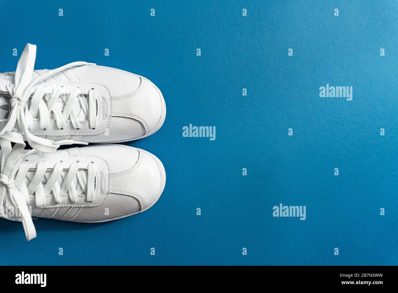 Sneaker bianche unisex su classico sfondo blu Foto Stock