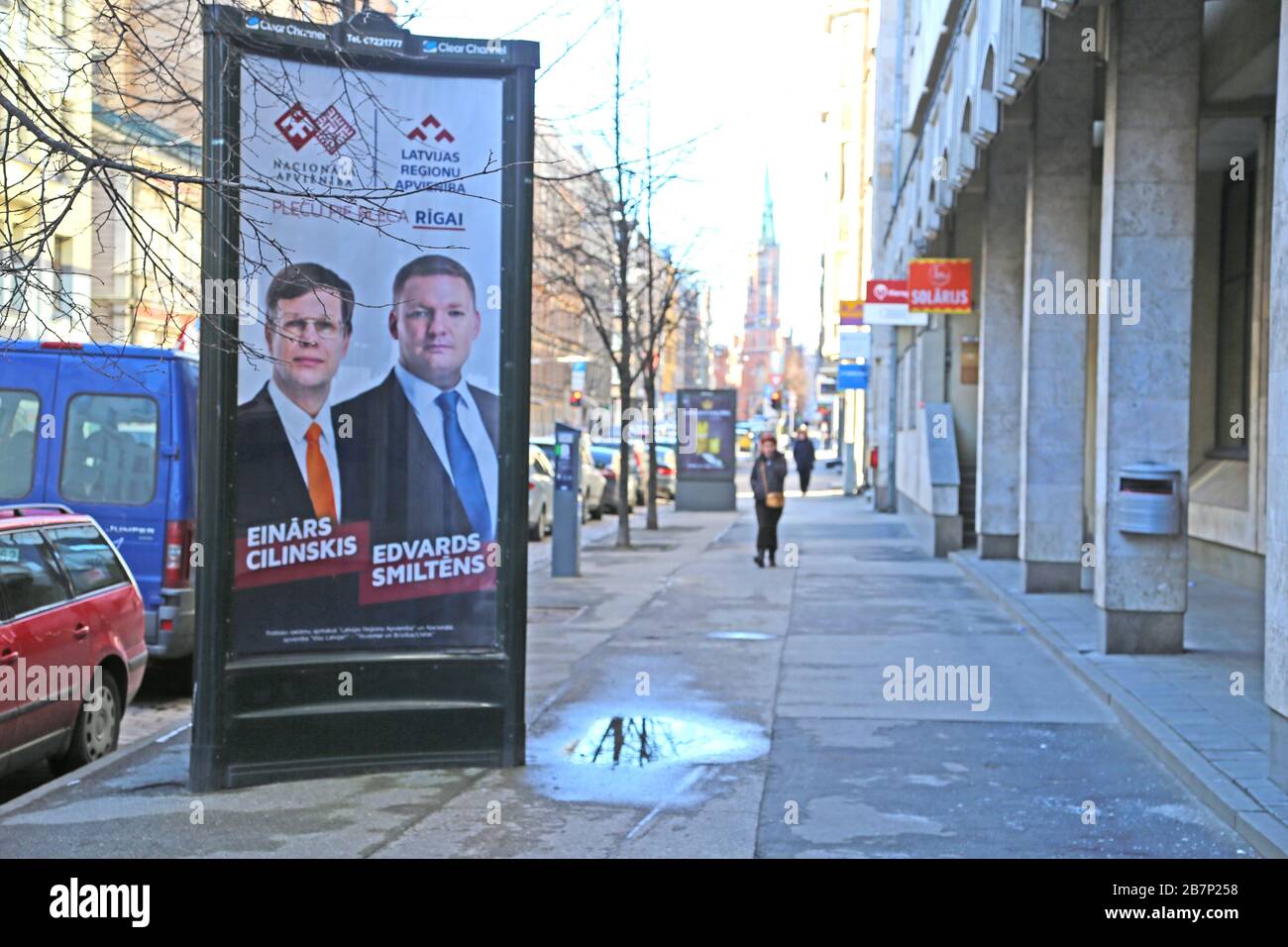 Riga, Lettonia. 15 Mar 2020. Un manifesto elettorale con i candidati Einars Cilinskis (l) e Edvards Smiltens del partito misto nazionale-conservatore Alleanza Nazionale e il partito di Centro dell'Alleanza delle regioni della Lettonia si trova in una strada nel centro della capitale lettone riga. Il poster riporta l'iscrizione 'Plecu pie pleca Rigai' (spalla a spalla per riga) Credit: Alexander Welscher/dpa/Alamy Live News Foto Stock