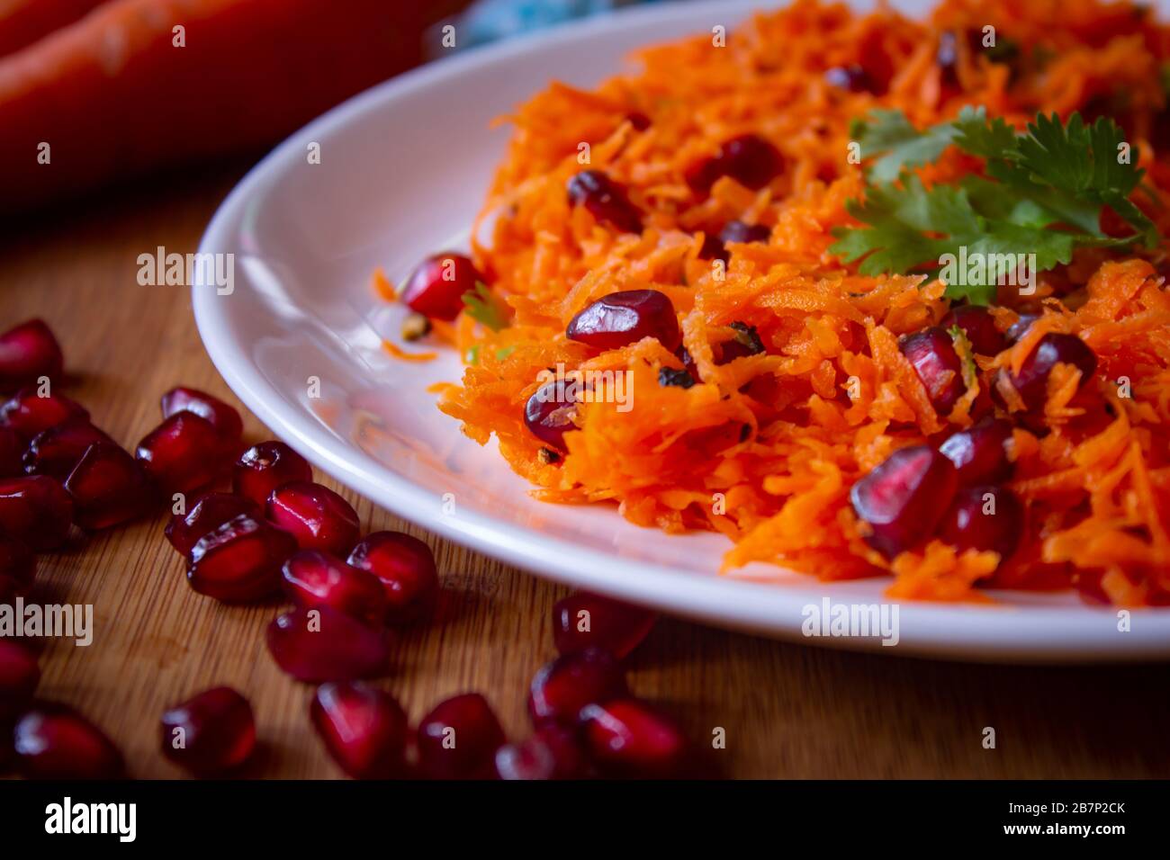 Insalata di carote e semi di melograno con condimento con coriandolo. Snack sano ricco di antiossidanti. Uso per concetto di salute. Foto Stock