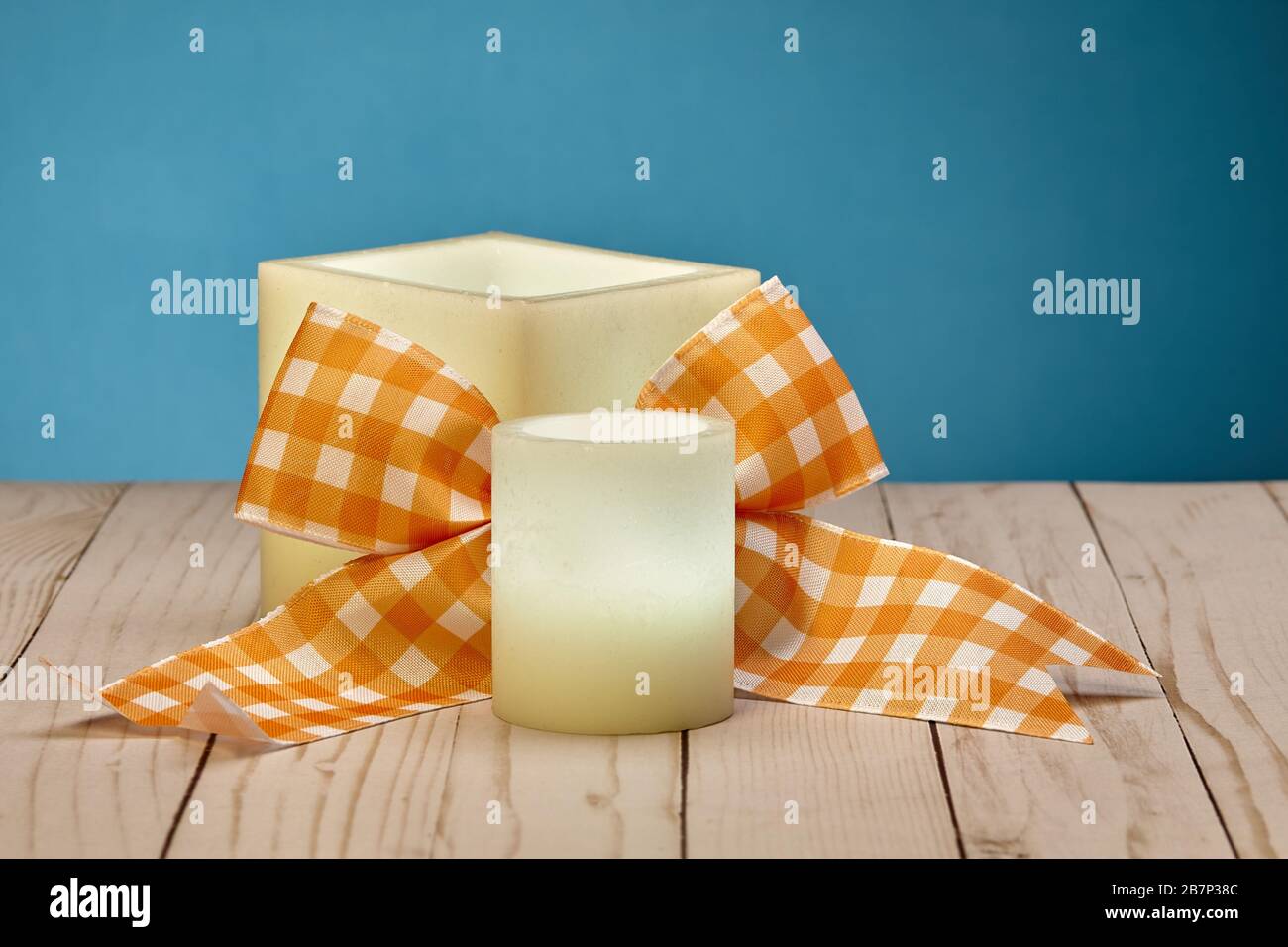 Coppia di candele di cera incandescenti e arco arancione Foto Stock