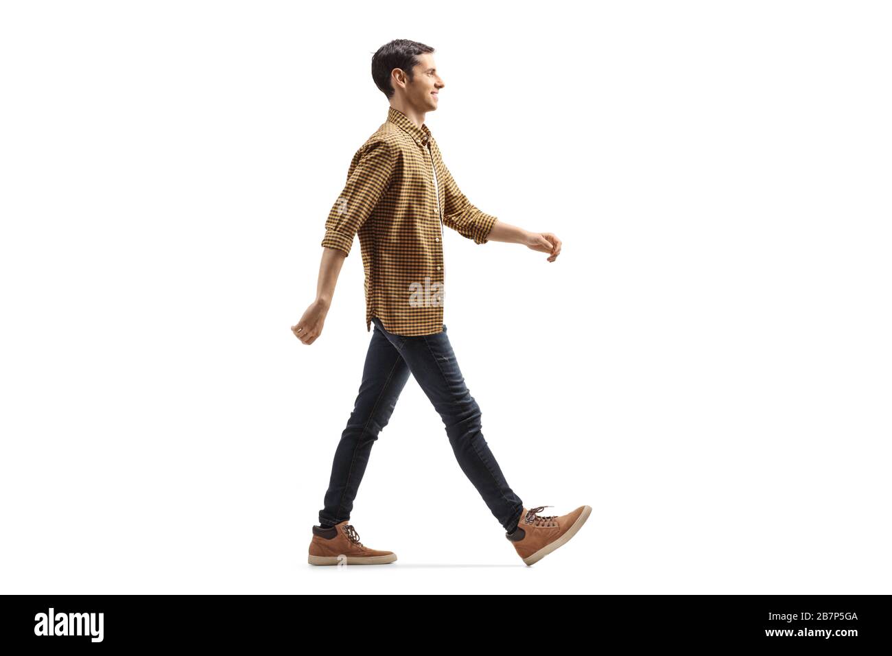 Scatto di profilo a tutta lunghezza di un giovane casual in camicia e jeans camminare con un sorriso isolato su sfondo bianco Foto Stock