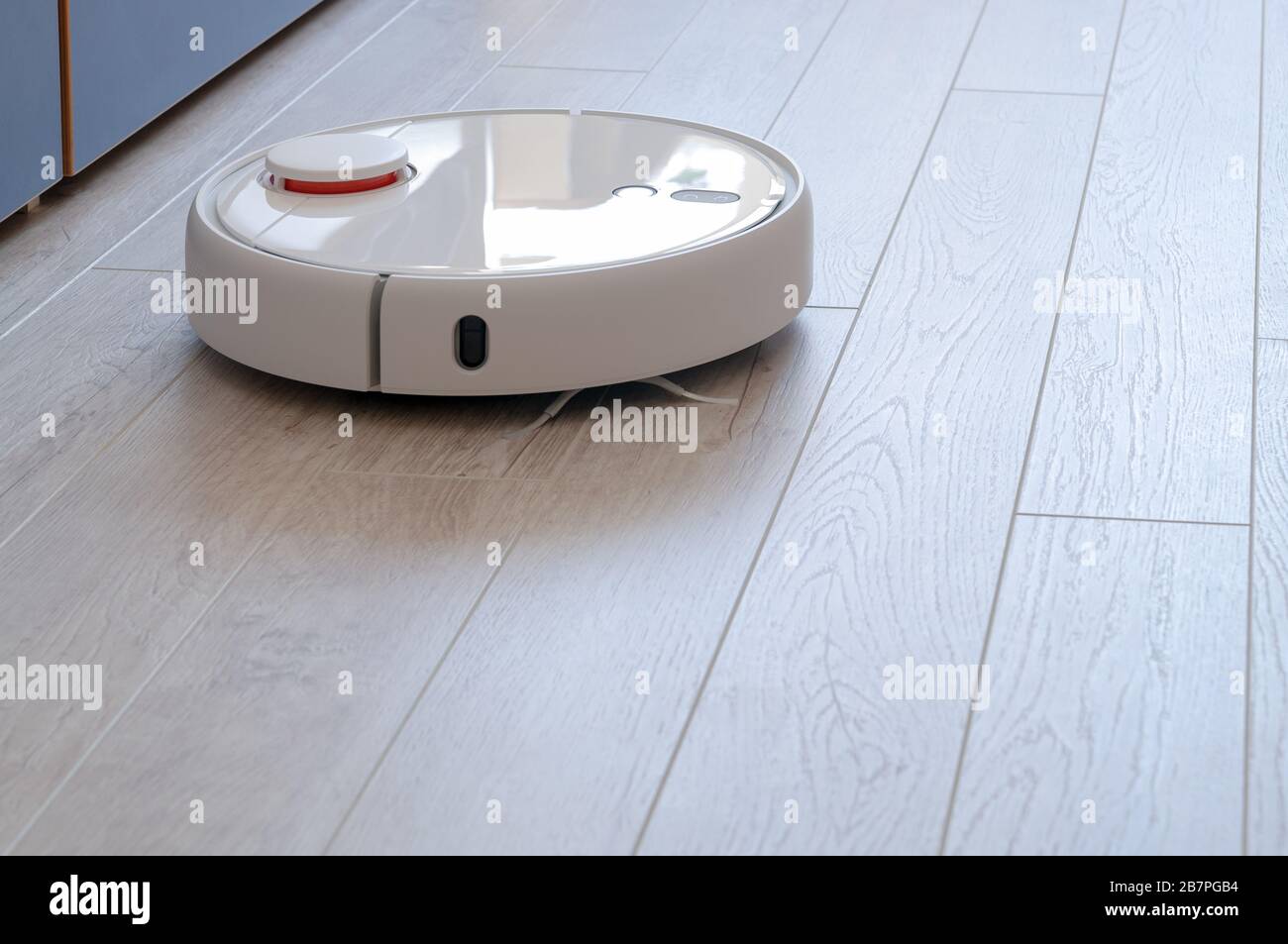 Robotica aspirapolvere sul laminato pavimento di legno smart la tecnologia di pulizia Foto Stock
