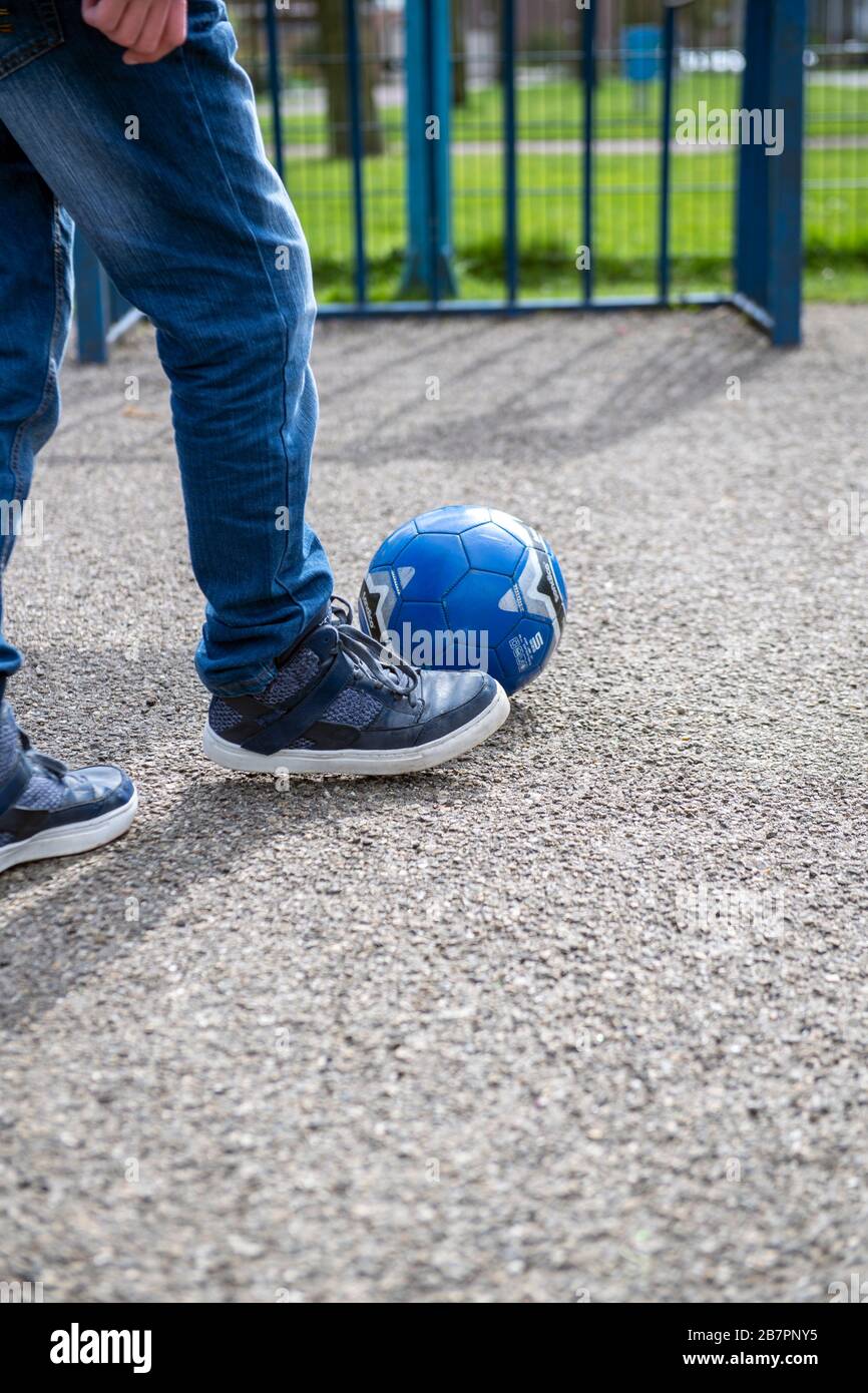 Teenager che calcia un calcio verso un obiettivo in un'area giochi all'aperto Foto Stock