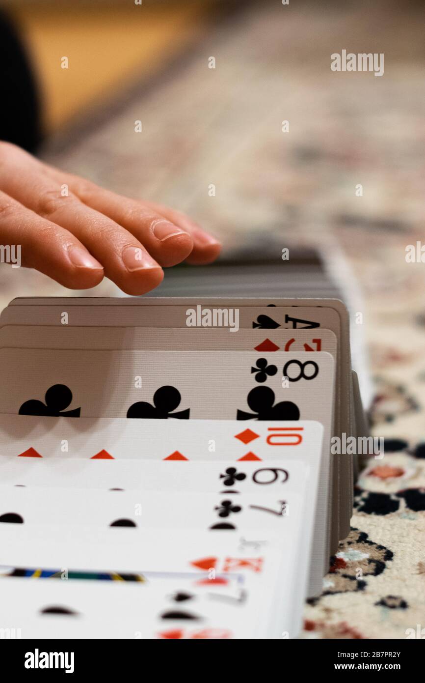 Una persona che fa un nastro sparso con le sue carte da gioco Foto Stock
