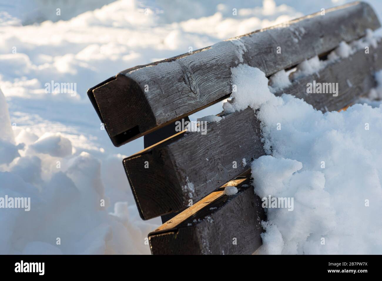Panca in legno coperta di neve in area esterna dopo forti nevicate Foto Stock