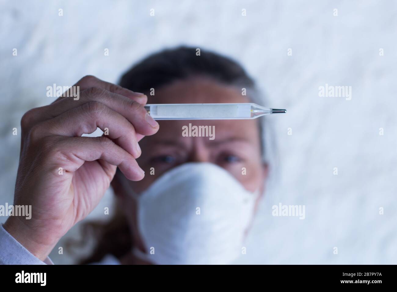 donna adulta con termometro e cinturino nella prevenzione del virus influenzale e del coronavirus Foto Stock