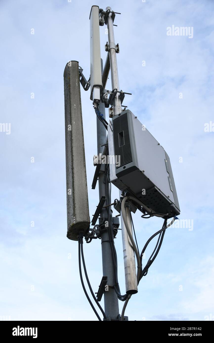 Antenna di rete per telecomunicazioni cellulari montata su un palo metallico che fornisce forti onde di segnale dalla parte superiore del tetto attraverso la grande città Foto Stock