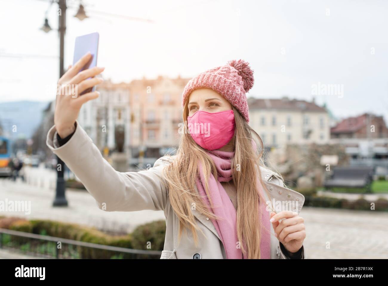 Donna che indossa la maschera corona facendo selfie con il telefono Foto Stock