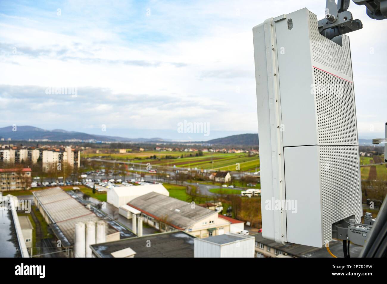 Nuova antenna di rete per telecomunicazioni radio 5G montata su un palo metallico che fornisce forti onde di segnale dalla parte superiore del tetto attraverso la grande città Foto Stock