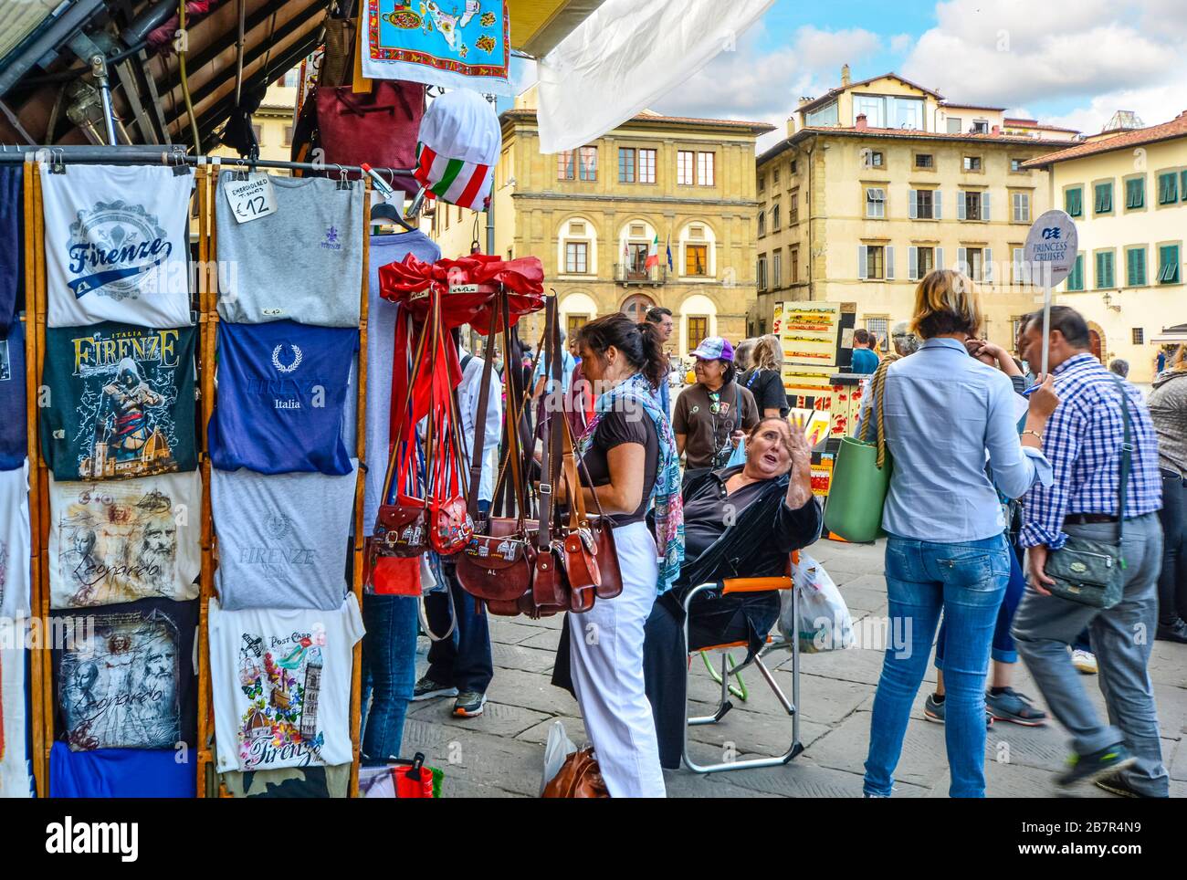 Turisti e guide turistiche acquistano souvenir e parlano con venditori locali e mercanti in un mercato all'aperto in Piazza Santa Croce a Firenze. Foto Stock