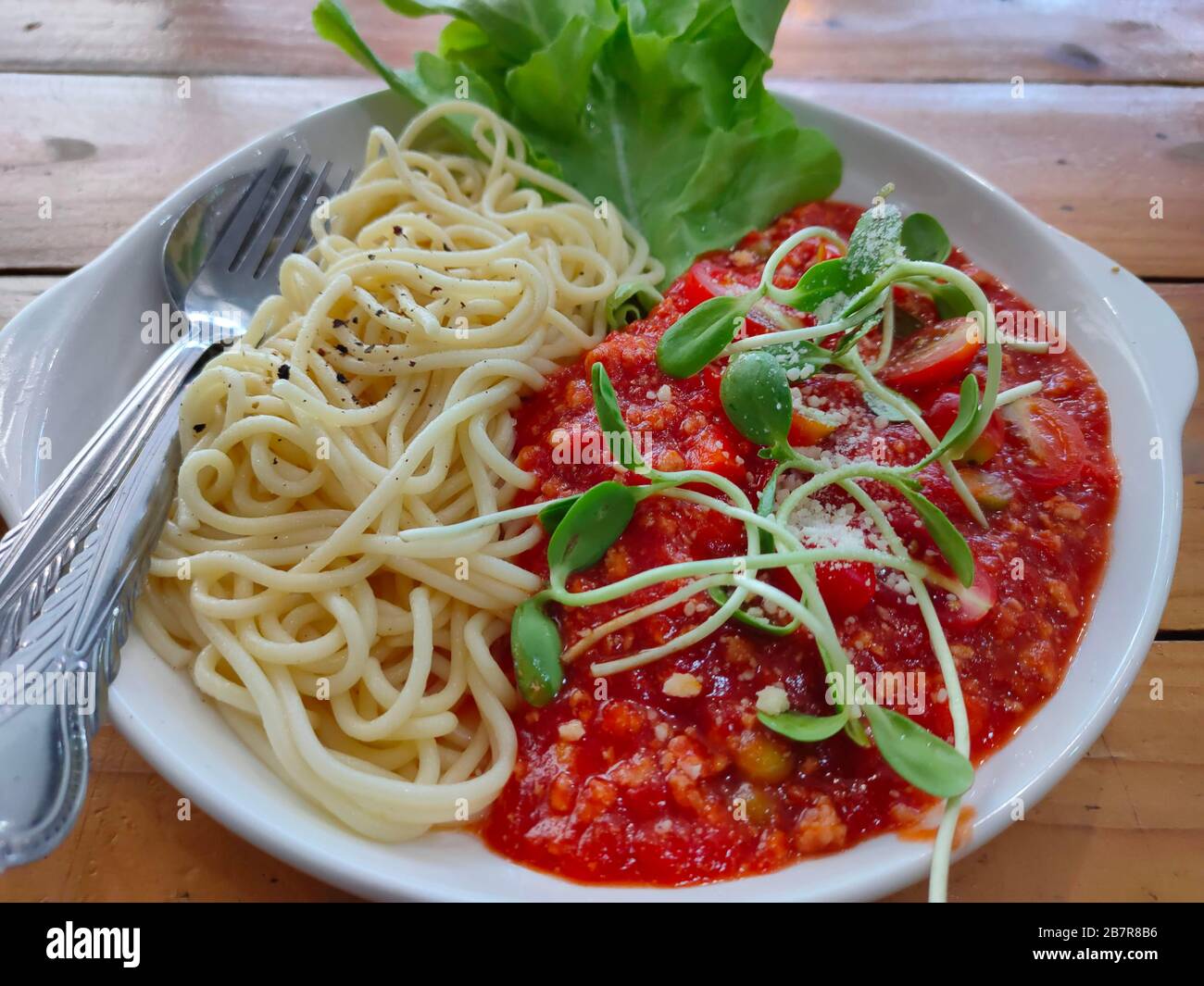 La gustosa e appetitosa pasta classica italiana spaghetti con salsa di pomodoro, parmigiano al formaggio e basilico sul piatto Foto Stock