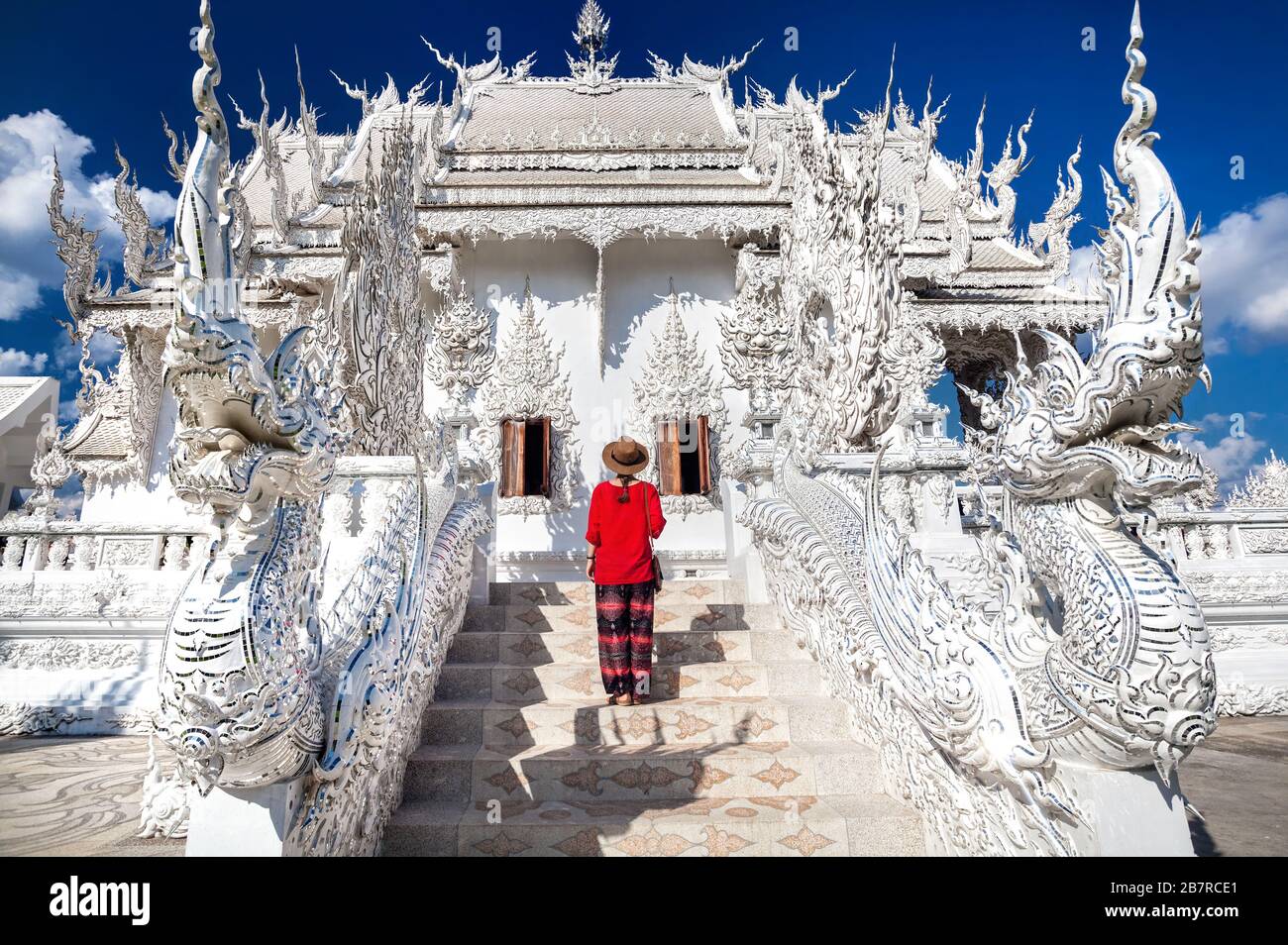 Donna in camicia rossa di fronte a Wat Rong Khun il Tempio Bianco a Chiang Rai, Thailandia Foto Stock