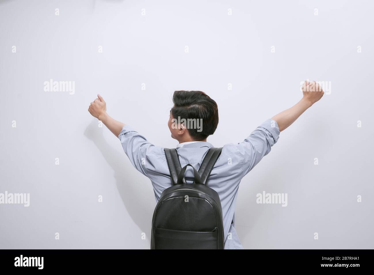 Vista posteriore di uno studente con le mani in aria celebrando il successo su sfondo bianco Foto Stock
