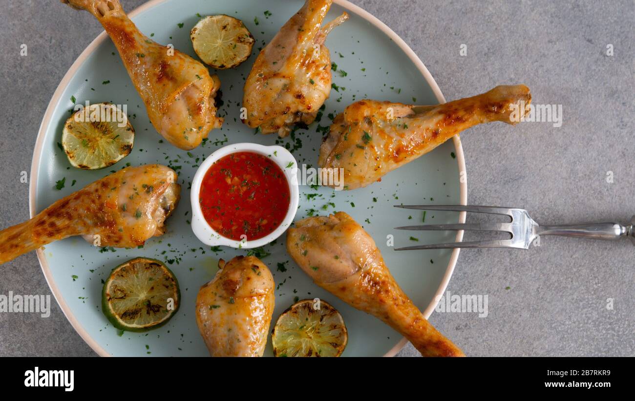 Cosce di pollo cotte su un grande piatto rotondo blu. Foto Stock