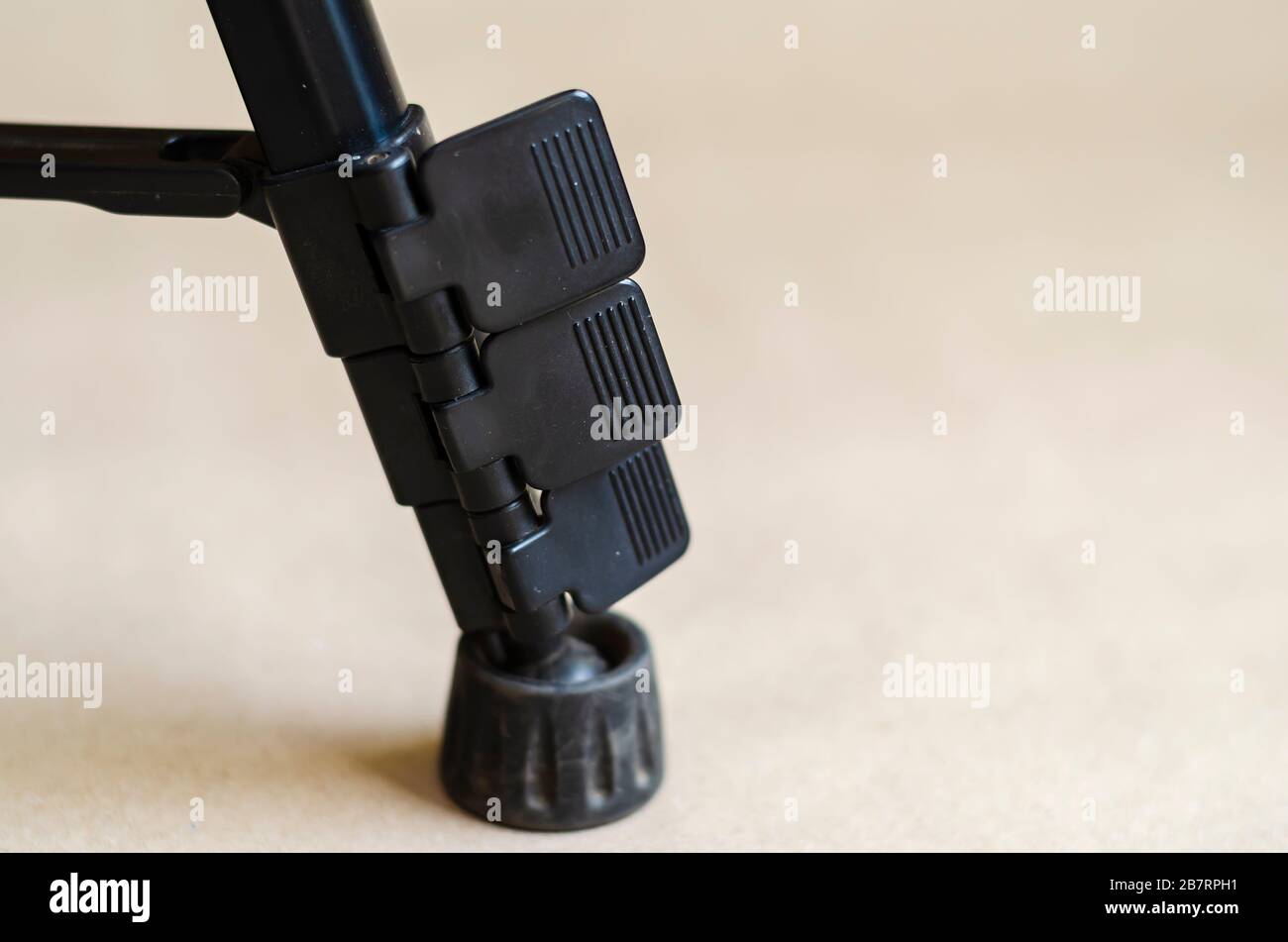 Primo piano della gamba del treppiede nero. Piede in metallo con bottoni in plastica nera. Attrezzatura fotografica. Vista laterale. Messa a fuoco selettiva. Foto Stock