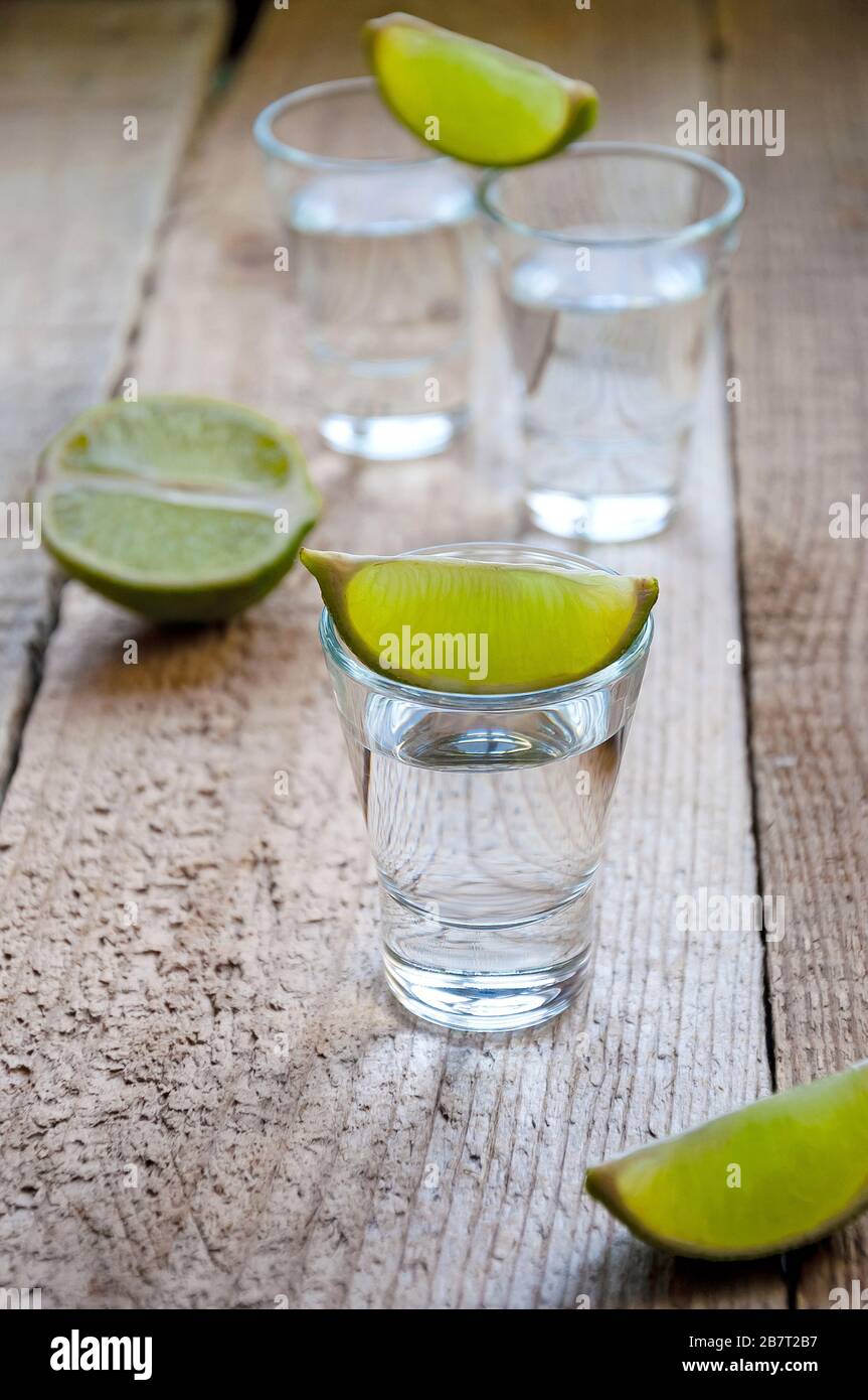 Bevanda alcolica. Tequila d'argento con lime sulla tavola di legno. Foto Stock