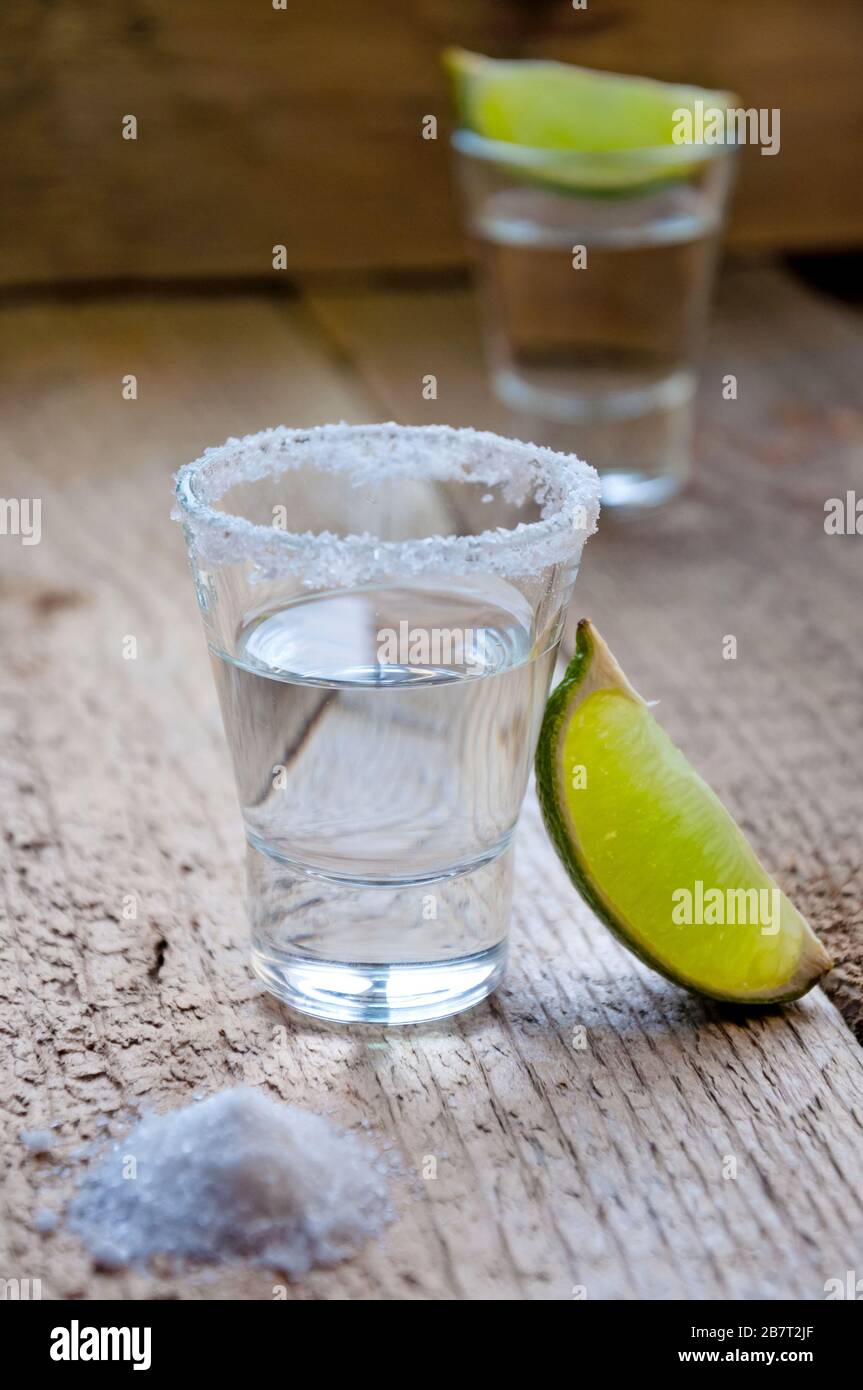 Bevanda alcolica. Tequila d'argento con lime e sale sulla tavola di legno. Foto Stock