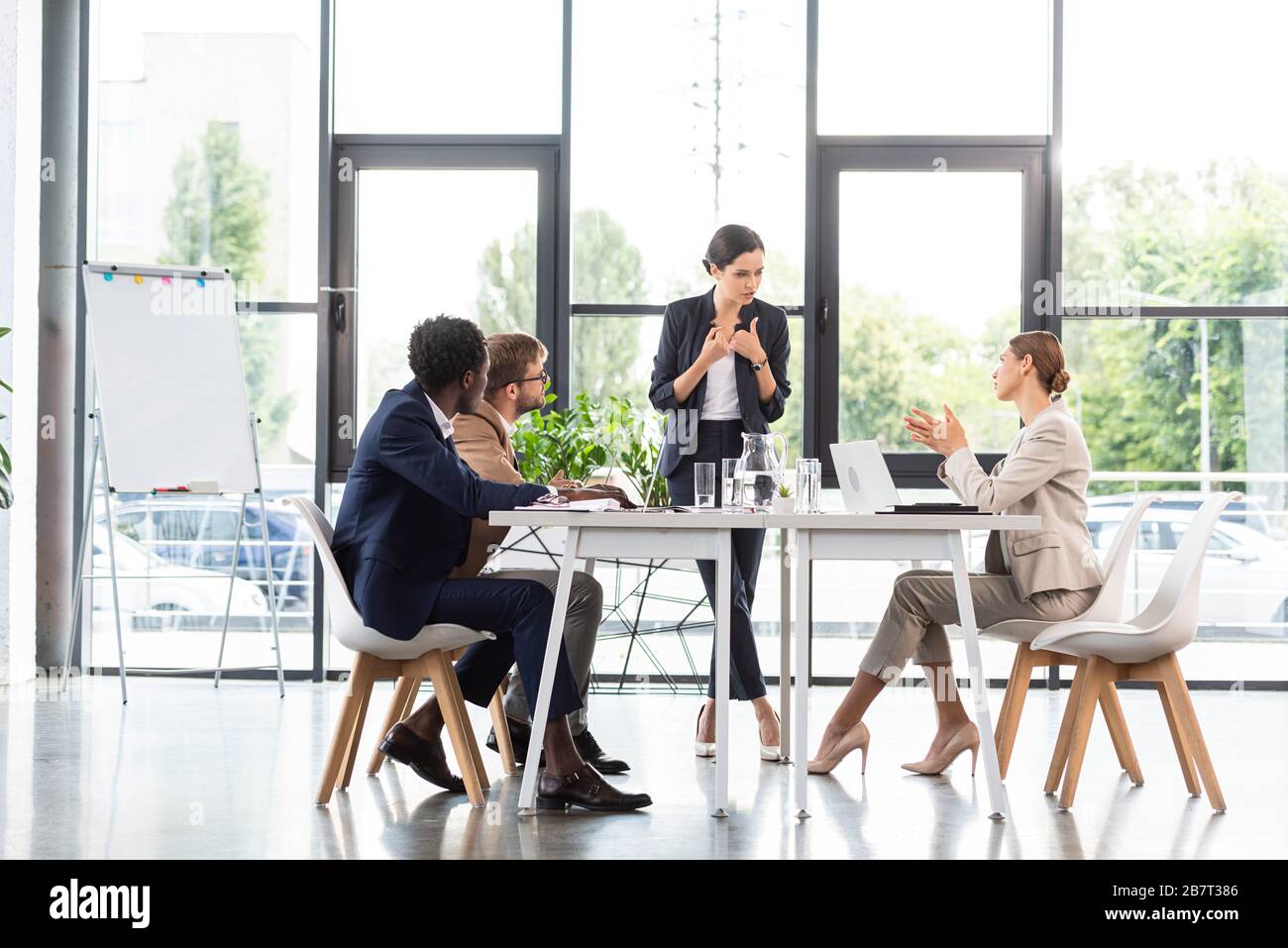 uomini d'affari multietnici seduti ai tavoli durante una conferenza in ufficio Foto Stock