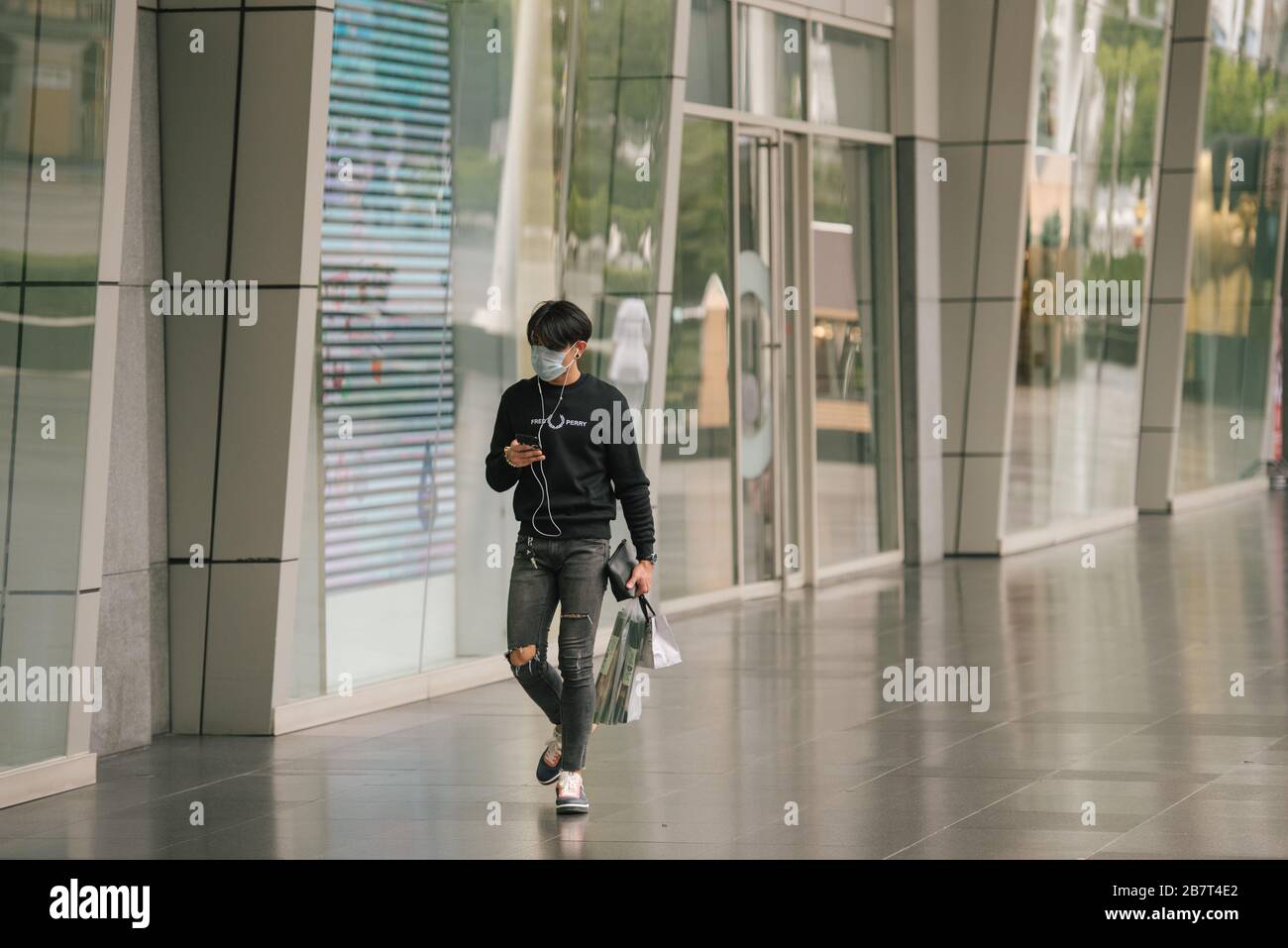 Un uomo che fa shopping al Central World di Bangkok, Thailandia. Egli è solo e non ci sono altri acquirenti nella zona a causa del Coronavirus. Foto Stock