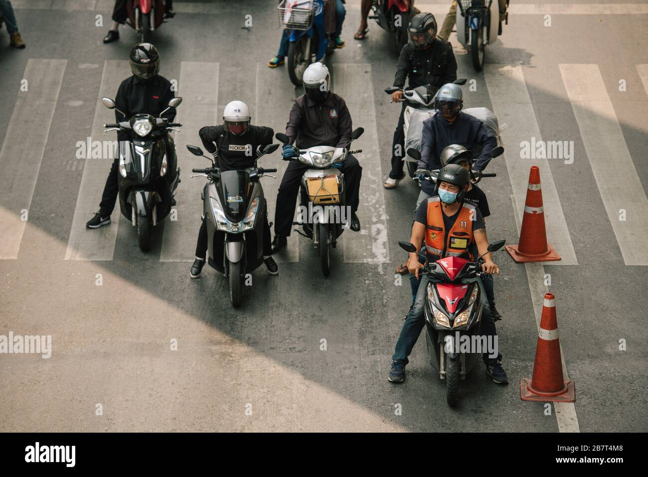 Moto taxi con maschera protettiva in attesa al semaforo tra Ratchadamri Road e Sukhumvit Road, Bangkok, Thailandia. Foto Stock
