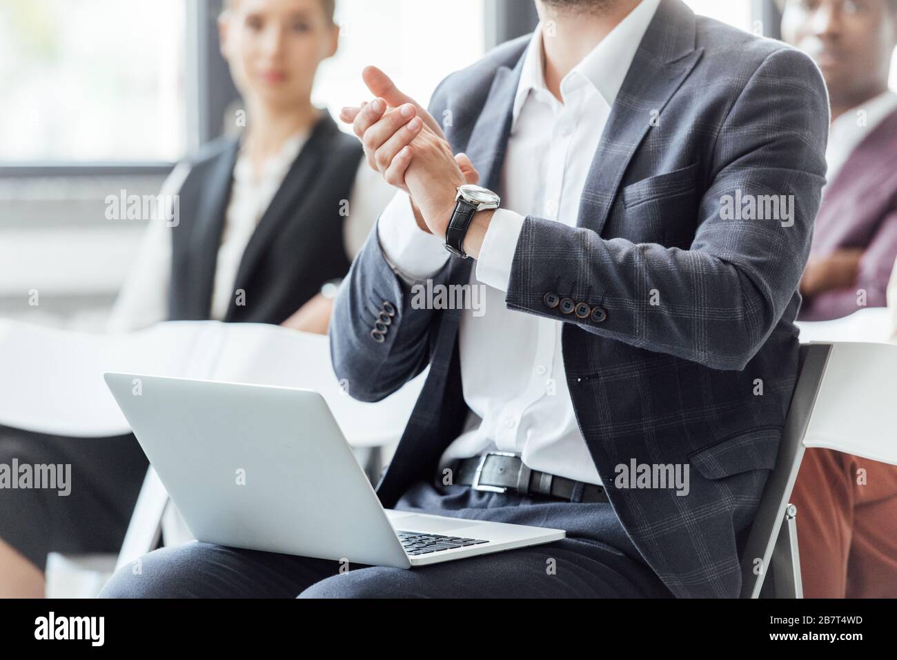 vista ritagliata dell'uomo d'affari in abbigliamento formale che tiene il laptop e applapping durante la conferenza Foto Stock