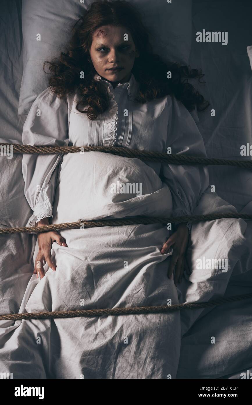 bambina ossessionata in un incubo legato con corda a letto Foto Stock