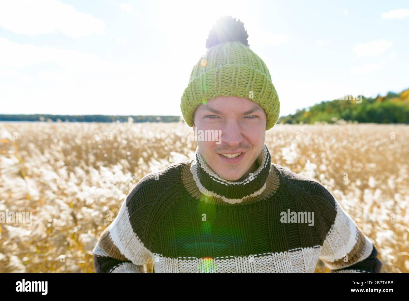 Felice giovane bell'uomo sorridente contro la vista panoramica del campo di torrida autunnale Foto Stock