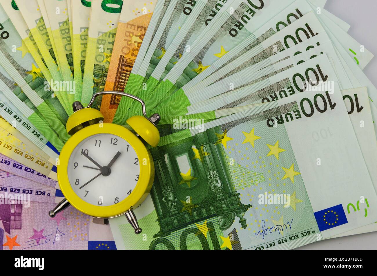 Sveglia gialla e banconote in euro di diverse denominazioni 2 Foto Stock