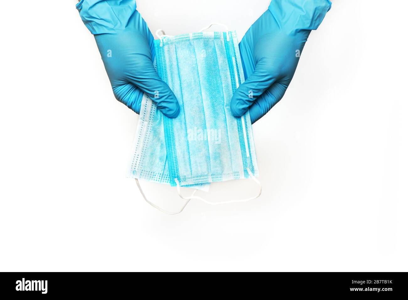 Mani in guanti per uso medico che trattengono maschere facciali di protezione isolate su sfondo bianco. Concetto di protezione del coronavirus Foto Stock
