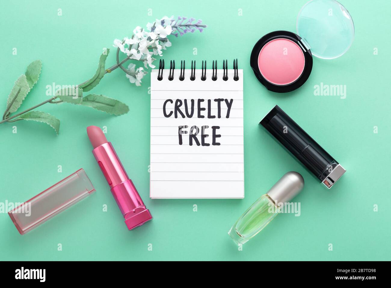 Cosmetici Cruely free, trucco con fiori su sfondo verde, vista dall'alto Foto Stock