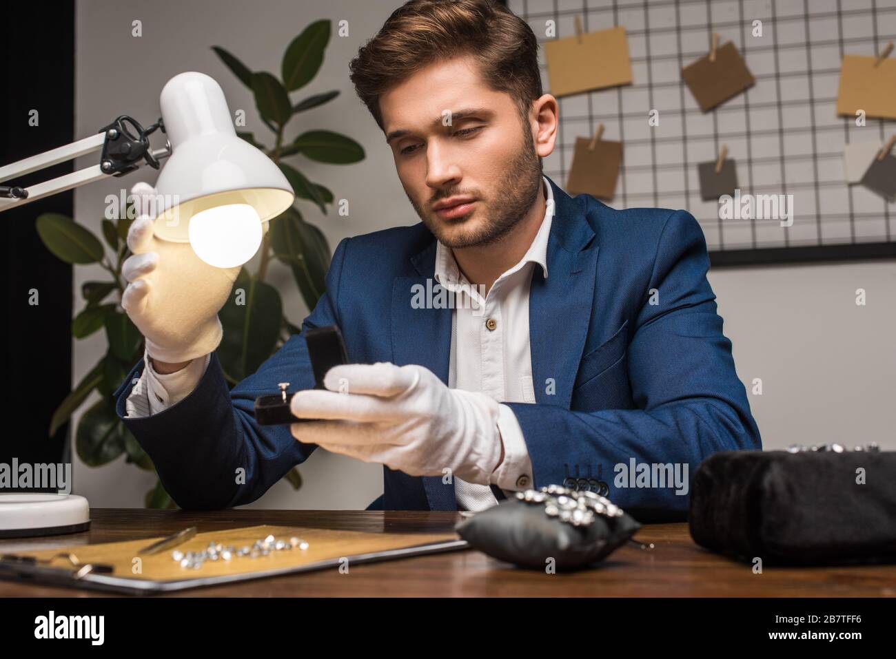 Bel gioiello appraiser anello di tenuta in scatola vicino lampada e gemstones e strumenti a tavola Foto Stock