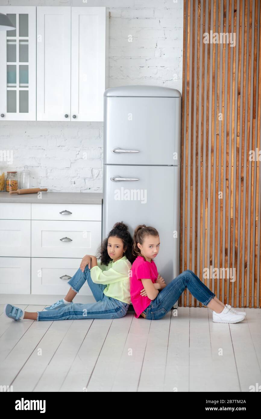Due ragazze che siedono sul pavimento che si sentono turbate Foto Stock