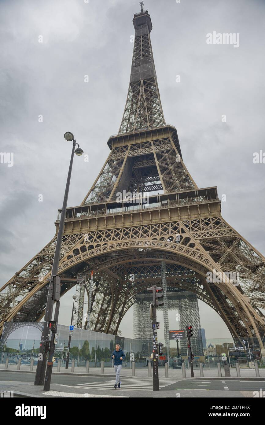 Parigi - 17 marzo 2020: Jogger solitario di fronte alla Torre Eiffel, come tutti i luoghi turistici sono chiusi a causa di un blocco ordinato. Foto Stock