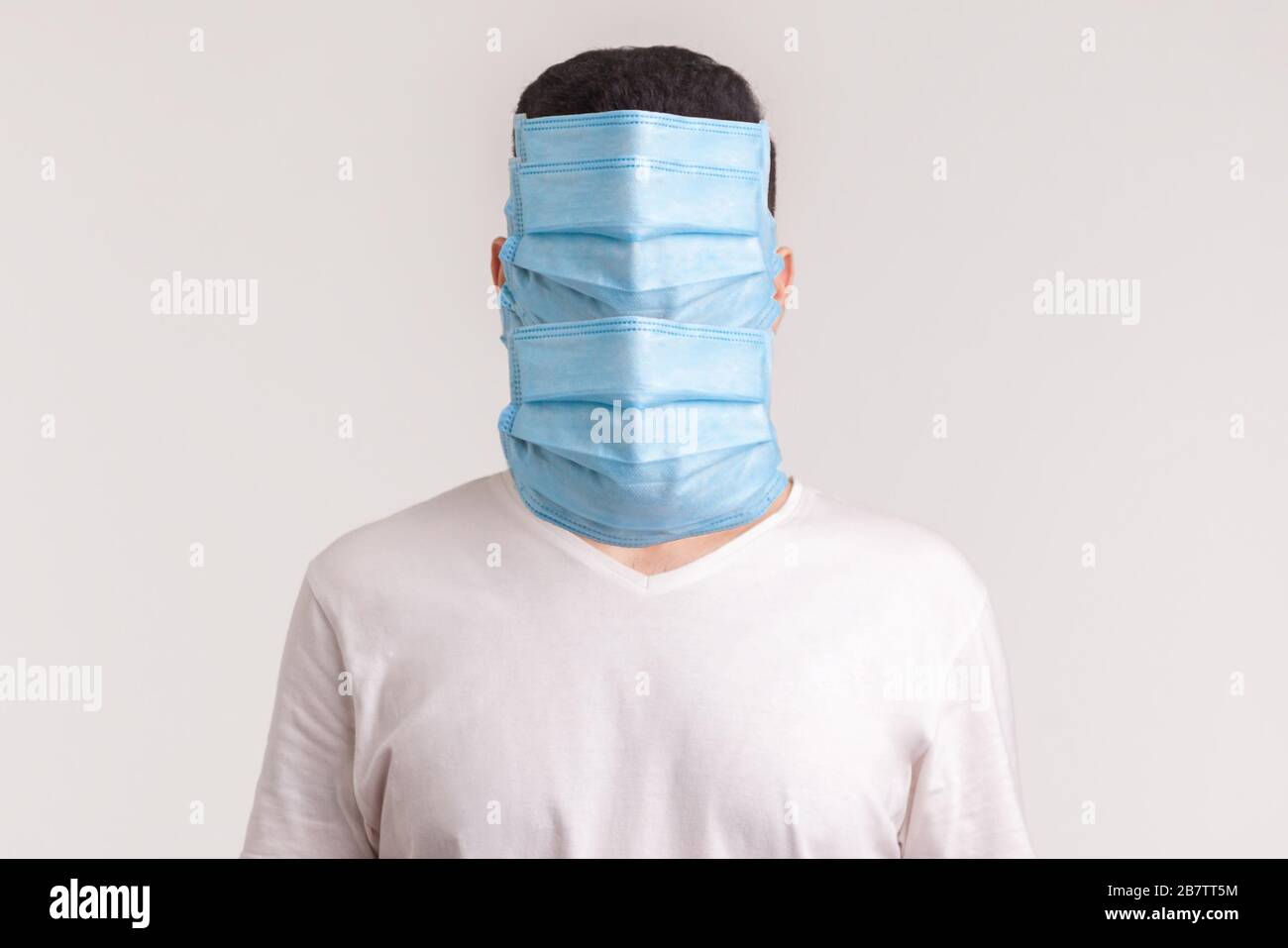 Protezione contro le malattie contagiose, coronavirus. Uomo pazzo di panico che indossa maschere igieniche per prevenire le infezioni, le malattie respiratorie trasportate dall'aria come Foto Stock