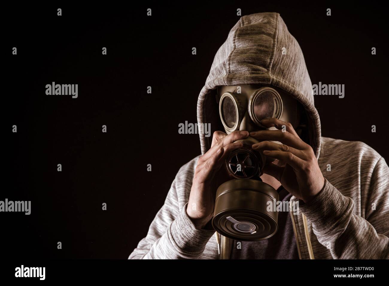 l'uomo mette su maschera di gas per proteggere contro il gas. Ritratto su sfondo nero, colorazione drammatica Foto Stock