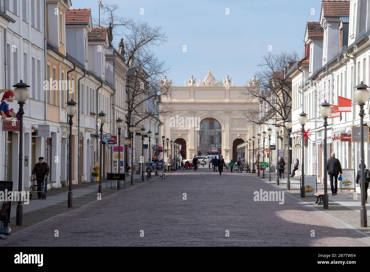 18 marzo 2020, Brandeburgo, Potsdam: Solo pochi passanti attraversano il Brandenburger Straße, che corre in direzione della porta di Brandeburgo, alle 11:19. Numerosi negozi nel viale dello shopping, che è altrimenti occupato nei giorni feriali, hanno dovuto rimanere chiusi a causa delle precauzioni corona. Foto: Soeren Stache/dpa-Zentralbild/ZB Foto Stock