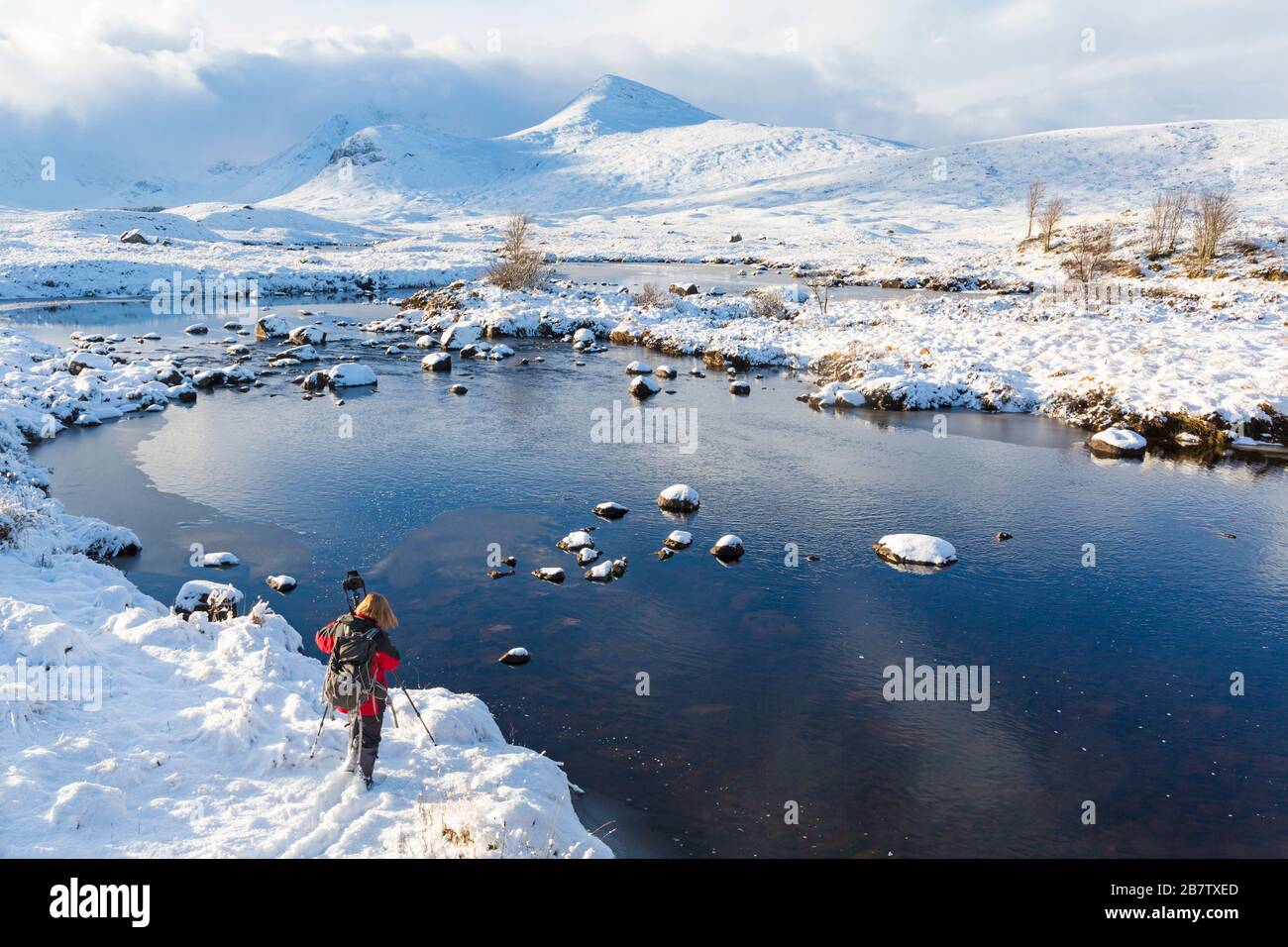 Fotografo nel freddo pomeriggio invernale con lago parzialmente congelato e neve a Loch Ba, Rannoch Moor, Argyll e Bute, Scozia nel mese di gennaio Foto Stock