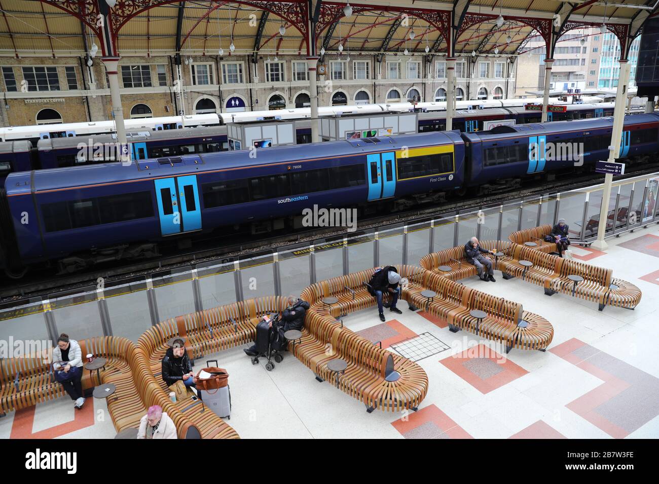 Una manciata di viaggiatori aspettano i treni alla stazione ferroviaria di Victoria a Londra, mentre i pendolari passano a lavorare da casa e il pubblico è invitato ad evitare i contatti sociali per impedire la diffusione del coronavirus. Foto Stock