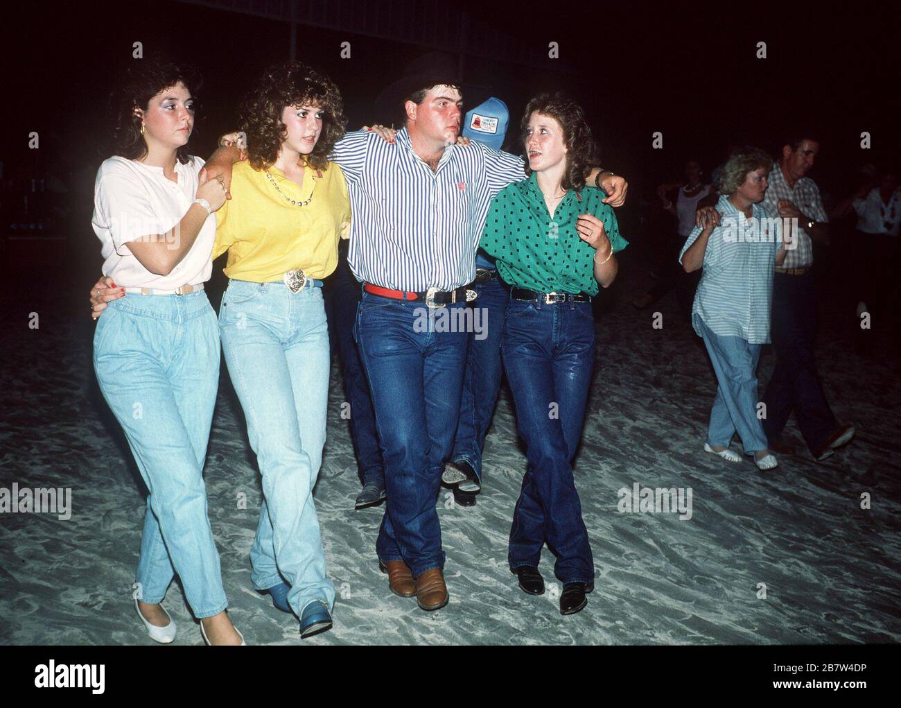 Stamford, Texas USA: Gruppo di amici che indossano jeans blu che ballano all'unisono durante la danza country e Western all'annuale riunione dei cowboy del Texas ©Bob Daemmrich Foto Stock