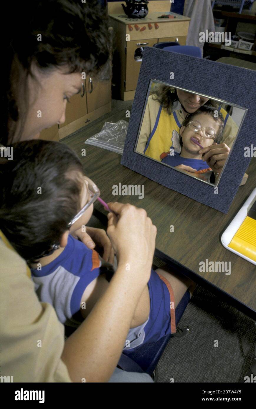 Terapista professionale che insegna al bambino disabile di spazzolarsi i denti e ridurre la sua sensibilità tattile. SIGNOR ©Bob Daemmrich Foto Stock