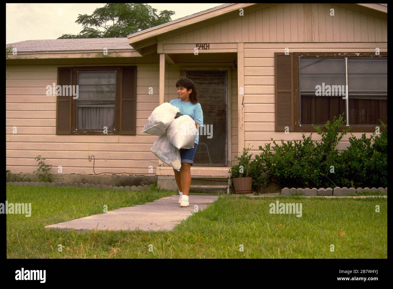 Austin Texas USA: Adolescente ispanico di 13 anni che porta fuori la spazzatura della casa MR ©Bob Daemmrich Foto Stock